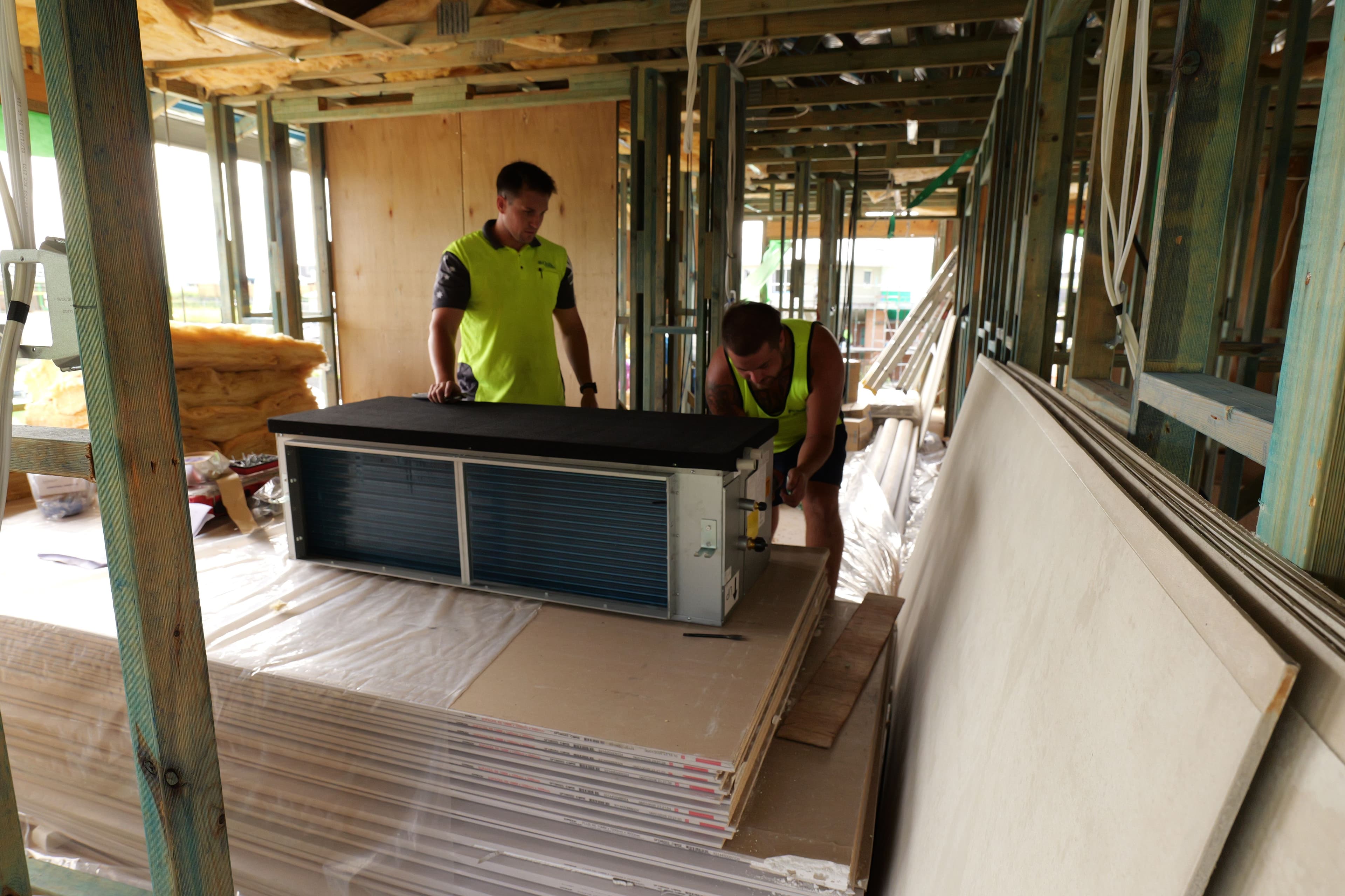Chillin team positioning ducted air conditioning equipment inside a framed home