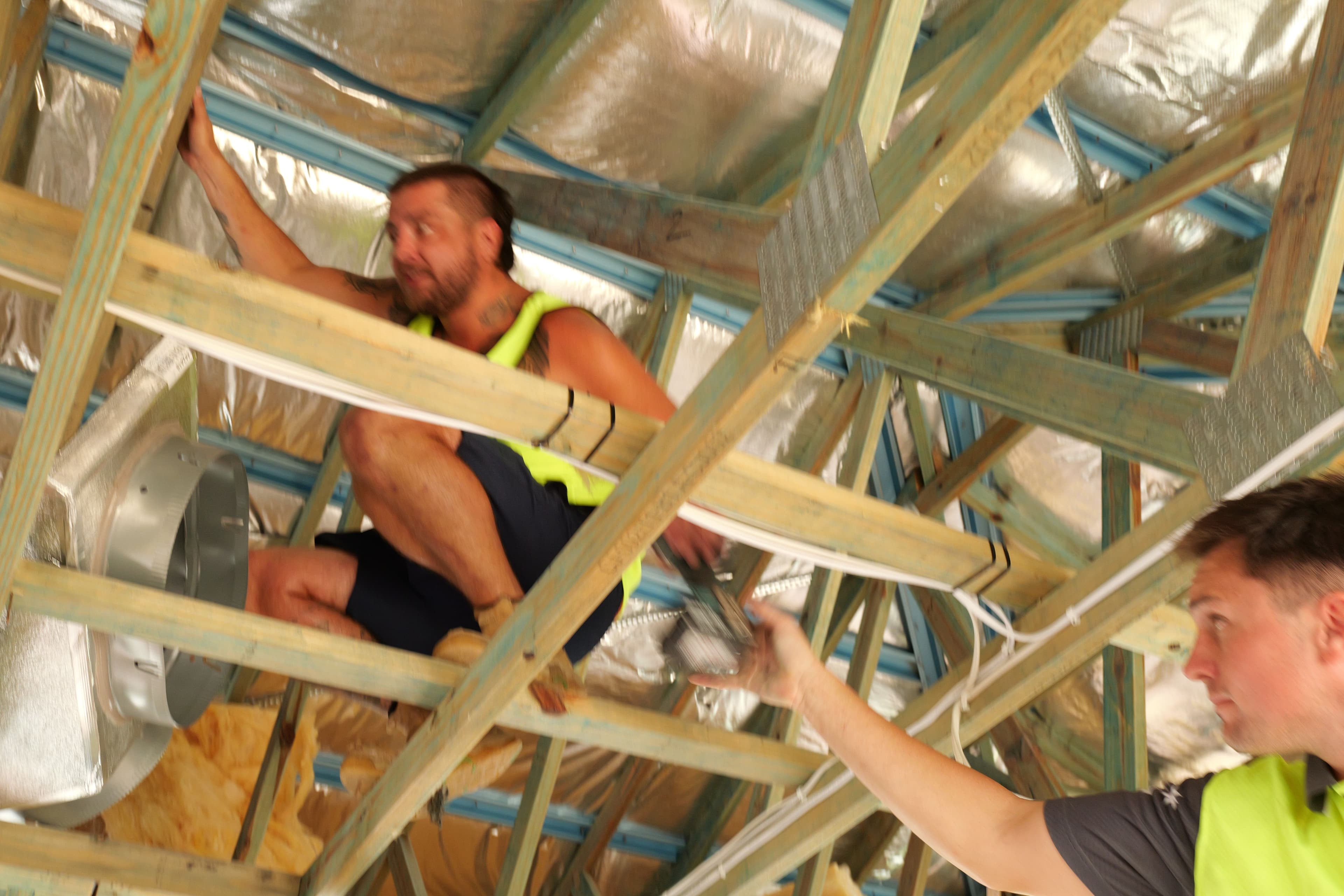 Chillin technician routing ductwork through roof framing